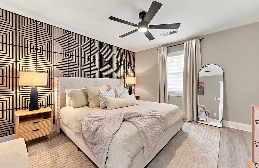 Primary bedroom with queen bed and geometric accent wall in a JAK Living condo